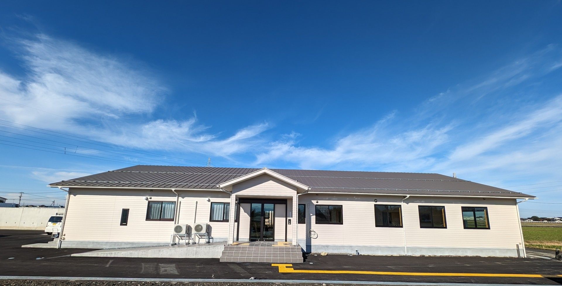 向かって左側にゆるやかなスロープがある白い外壁の平屋建てグループホーム