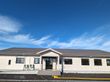 向かって左側にゆるやかなスロープがある白い外壁の平屋建てグループホーム
