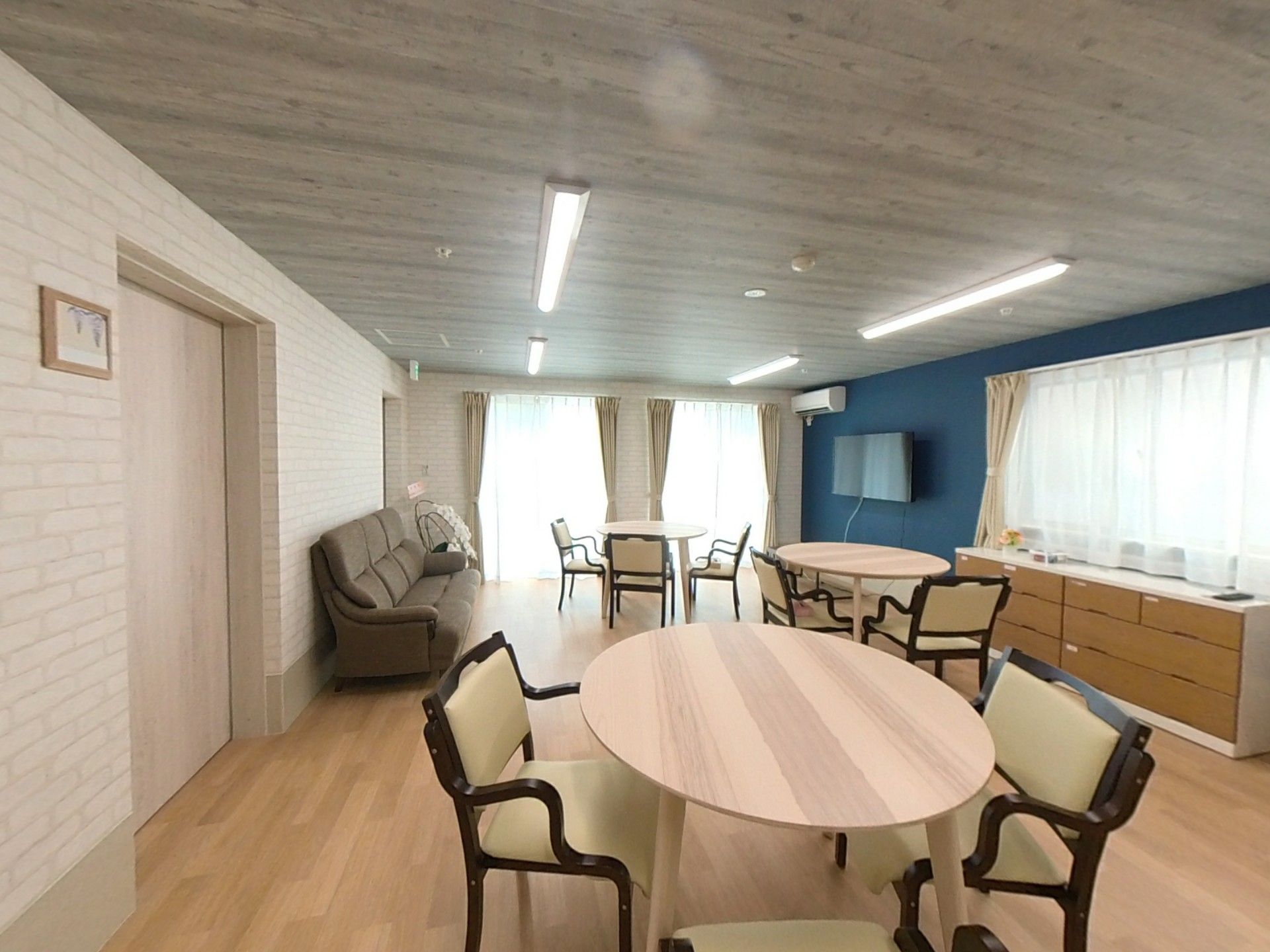 ベージュと紺の外壁で三角屋根の3階建てグループホーム
