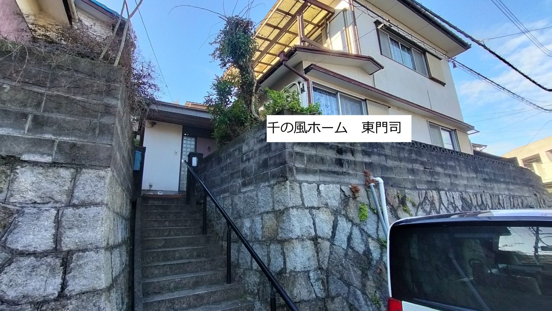 正面に階段があり、ベージュの外壁の2階建て住宅