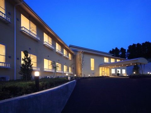 窓から温かい光が溢れており、手入れの行き届いた植え込みが美しい建物である。玄関へはゆるいスロープがつながっている。