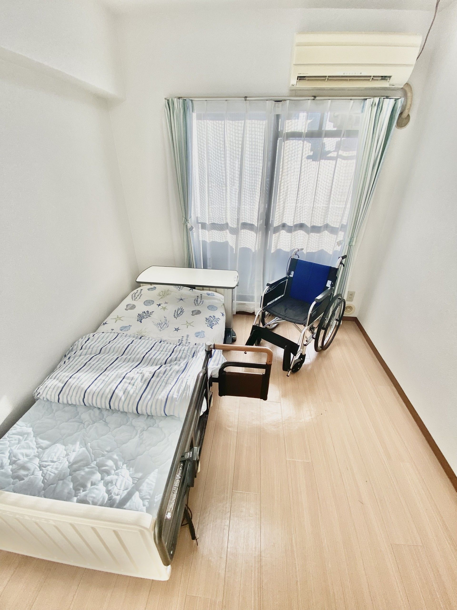 介護用ベッドと車いす、エアコンがある個室