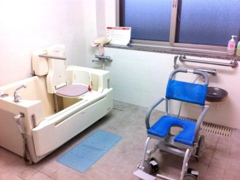 浴室には座った状態で入浴が可能な介護浴槽と、青い座面の車椅子が設置されている。お体の不自由な入居者様もご入浴を楽しめる。