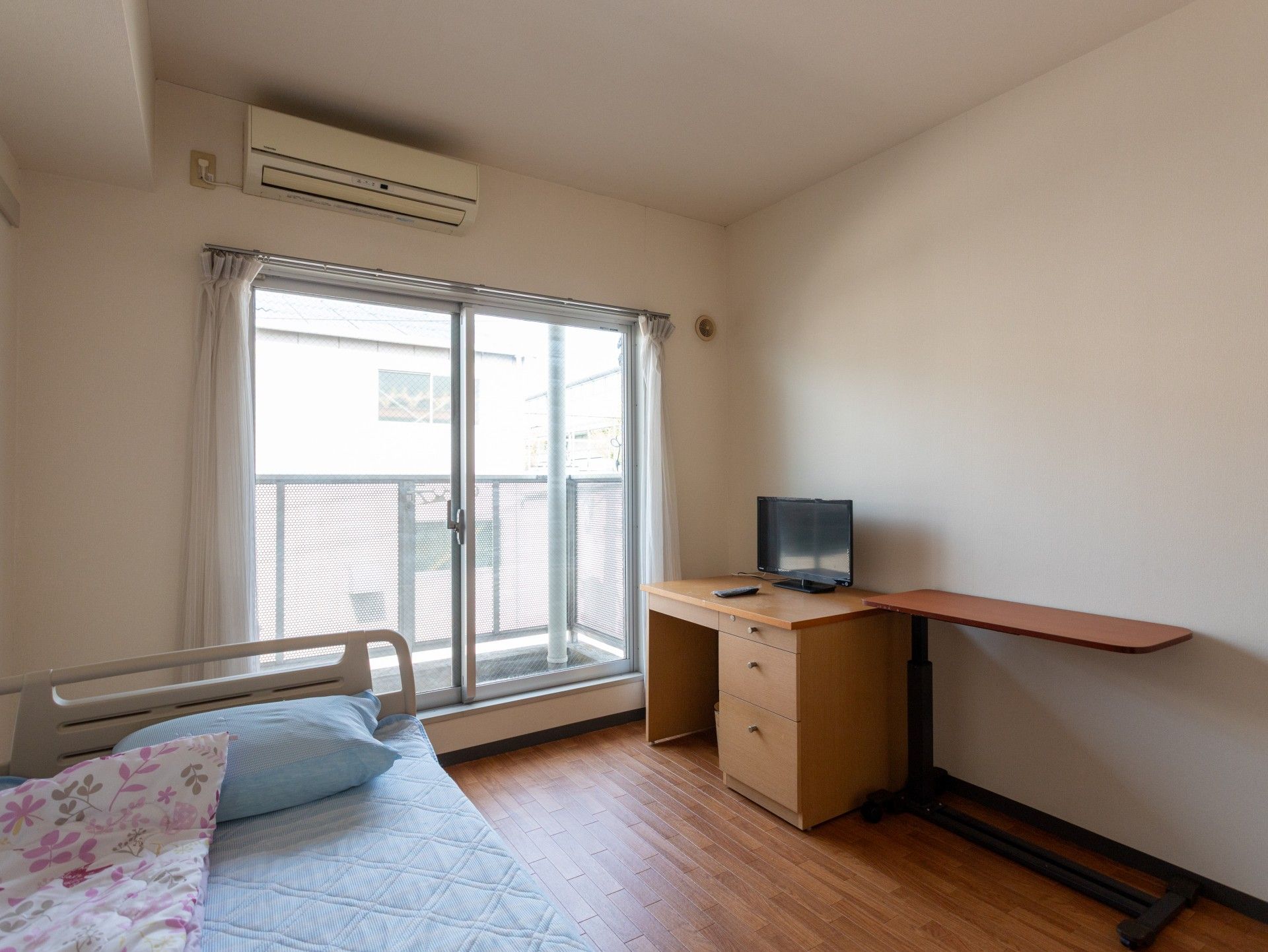 窓際のベッドと机の部屋