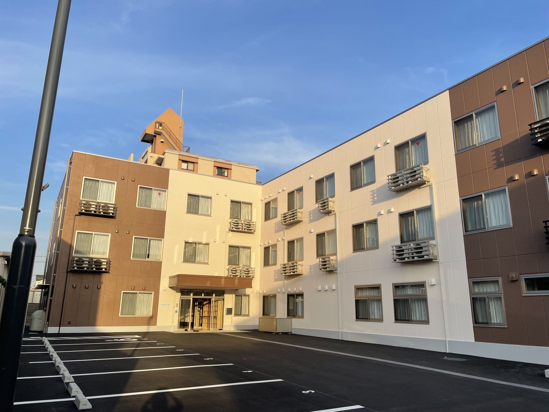 茶色とアイボリーの外壁の3階建て老人ホーム