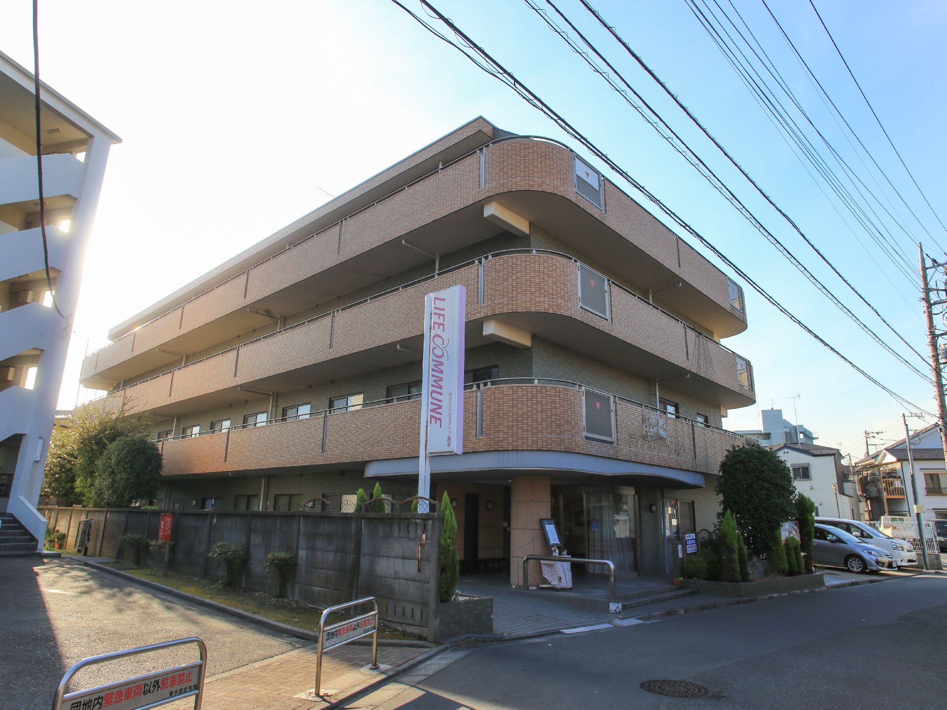 建物の前に緑の木々が植えられている、四階建ての施設外観