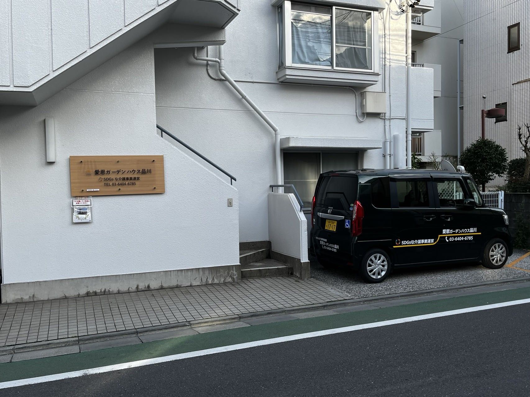 愛恩ガーデンハウス品川と書かれた看板が掲げられ、黒い車両が止まっている住宅