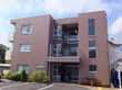 ３階建てのブラウンのマンションタイプの建物である。全ての階にはベランダが備わり、整備された駐車場がある。