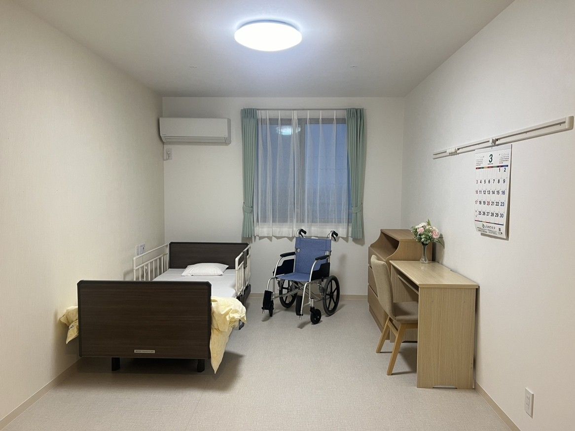 介護用ベッドと車椅子、机といすが設置されている個室