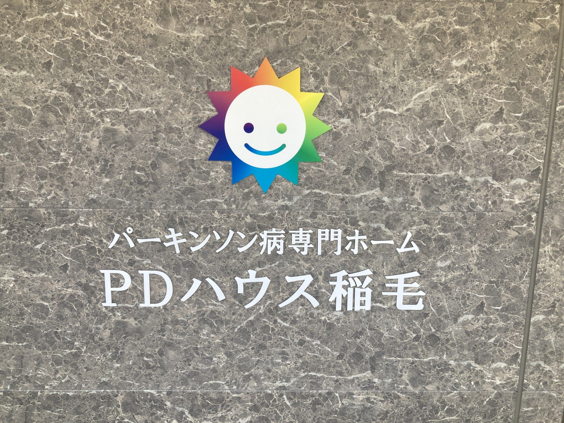 笑顔のロゴと施設名の壁