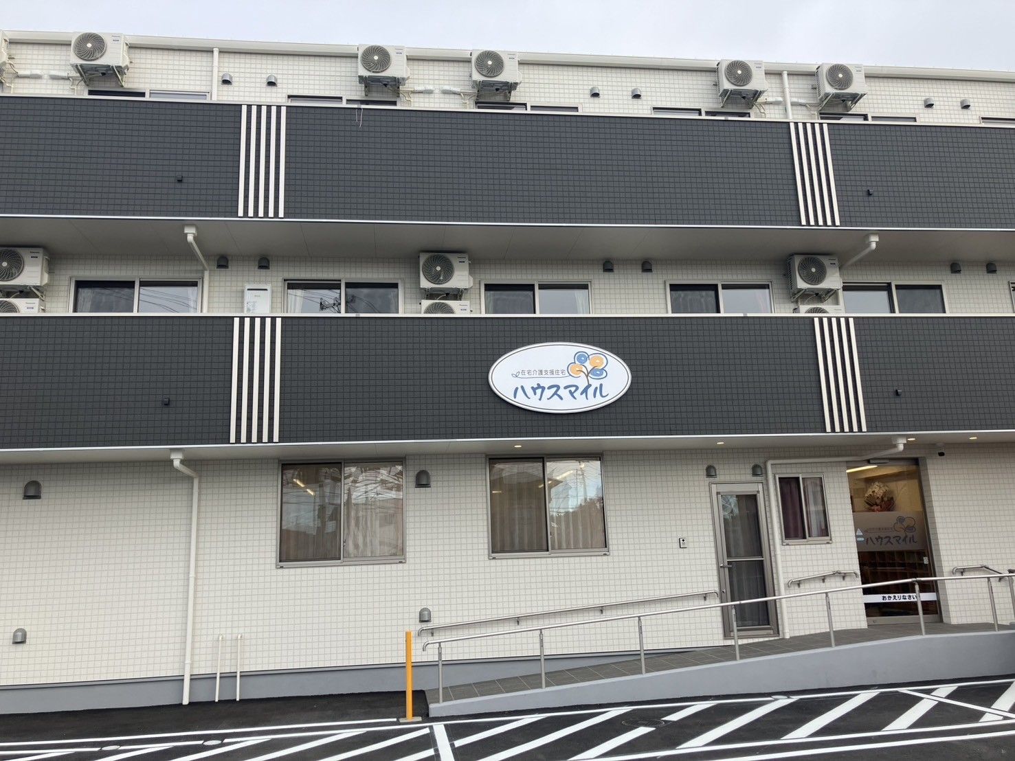 ハウスマイルの表示がある白い外壁の3階建て住宅