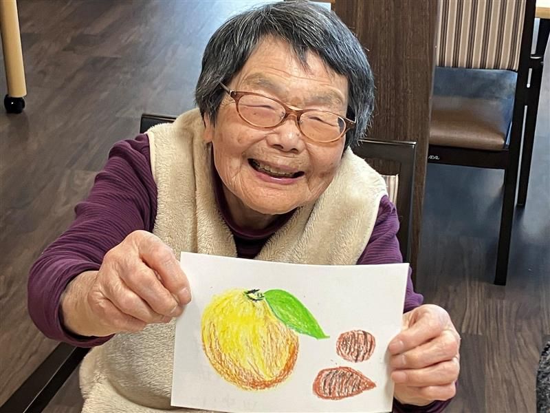 笑顔で絵を見せる女性