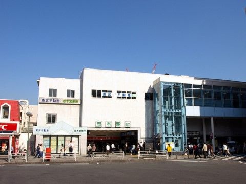 最寄駅の外観。２階建ての駅舎にはエレベーターが設置されている。駅周辺は商業地になっていて、様々な店舗がある。