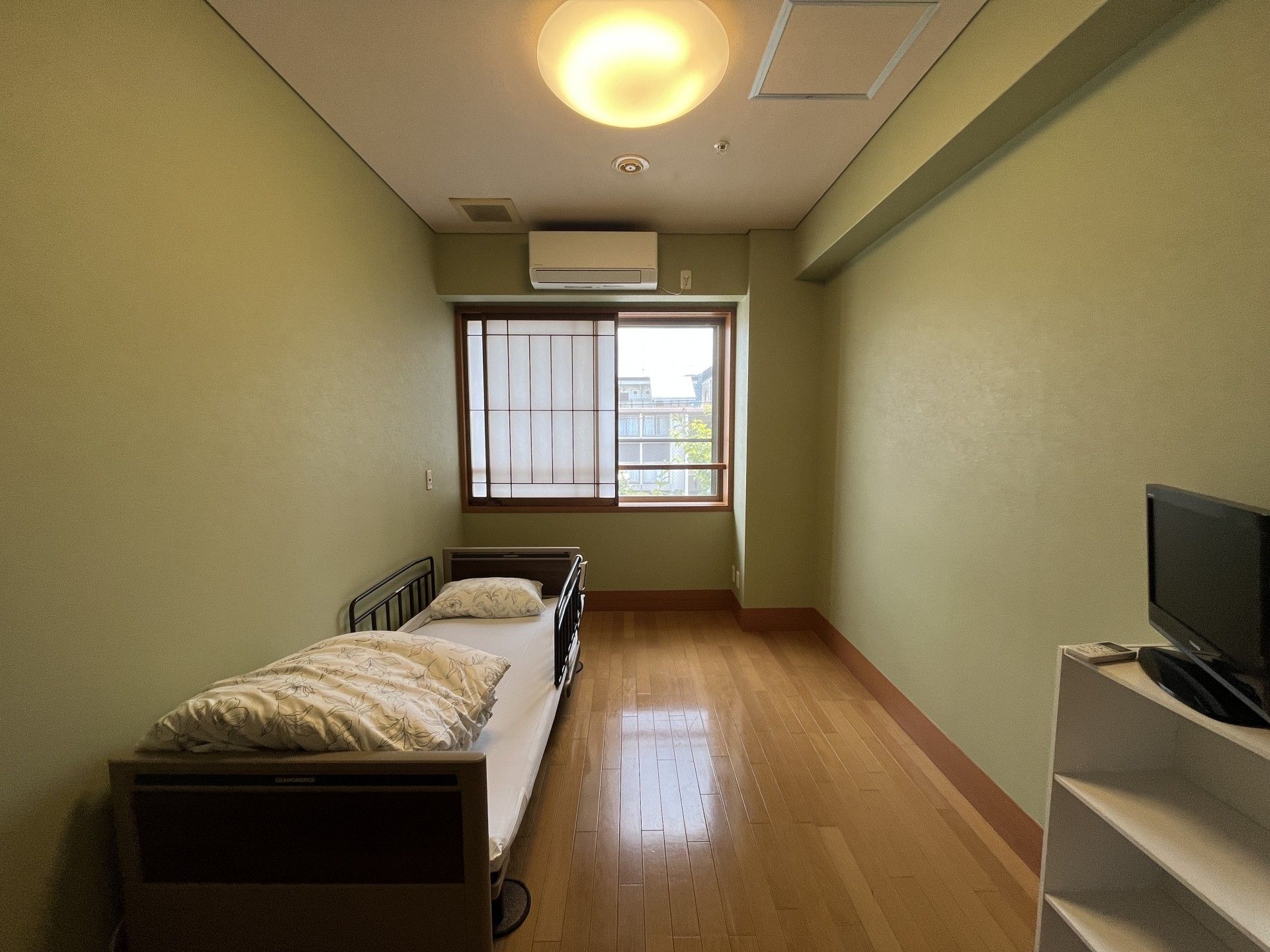 窓際のベッドと棚の部屋