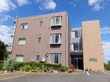 施設は外壁がベージュ色の３階建ての建物である。外階段が設置されており、建物前に広い駐車場が設けられている。