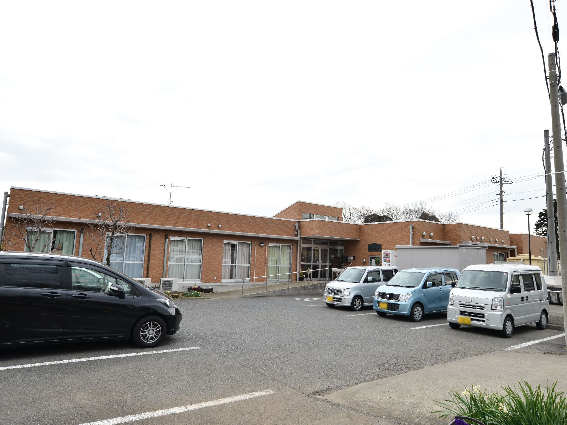 十分な広さのある駐車場越しに見た施設。建物はほぼ平屋であり入り口にコンクリートでスロープが作られている。