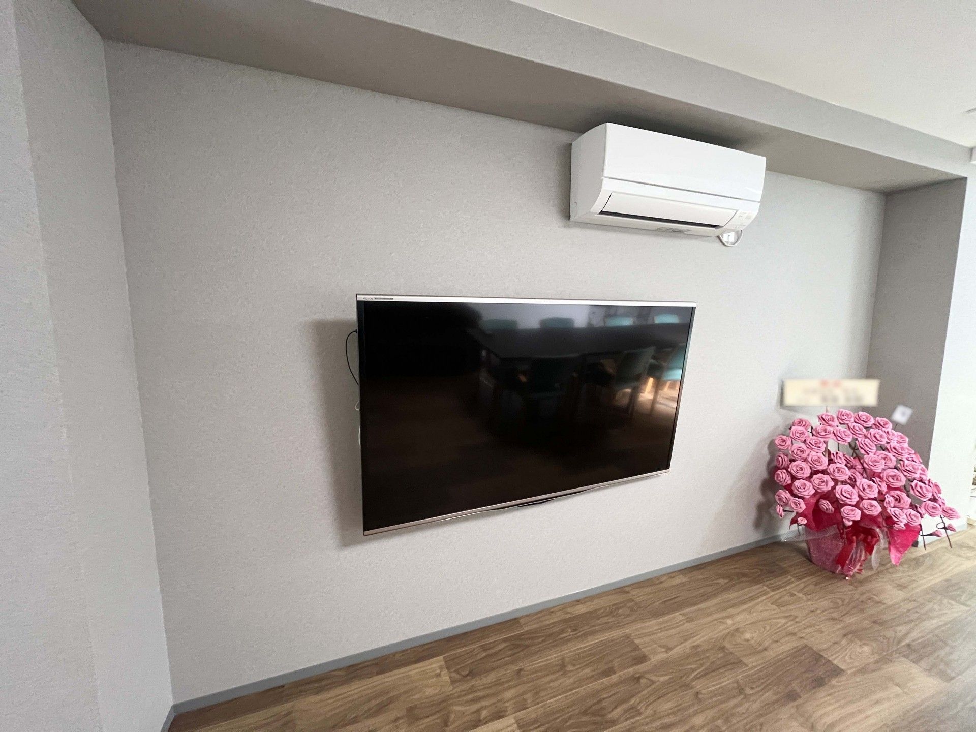壁掛けテレビと花のある部屋
