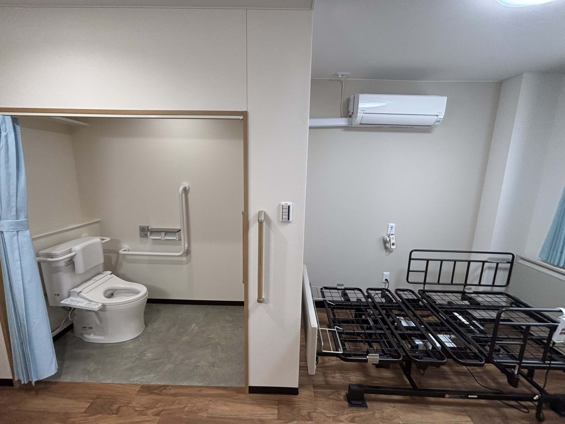 手すり付きのトイレとベッド