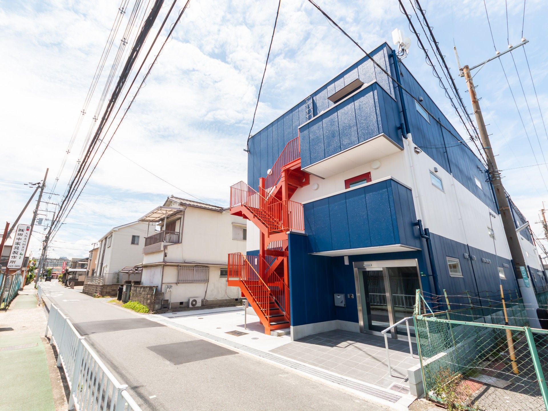 青い外壁と赤い階段の建物
