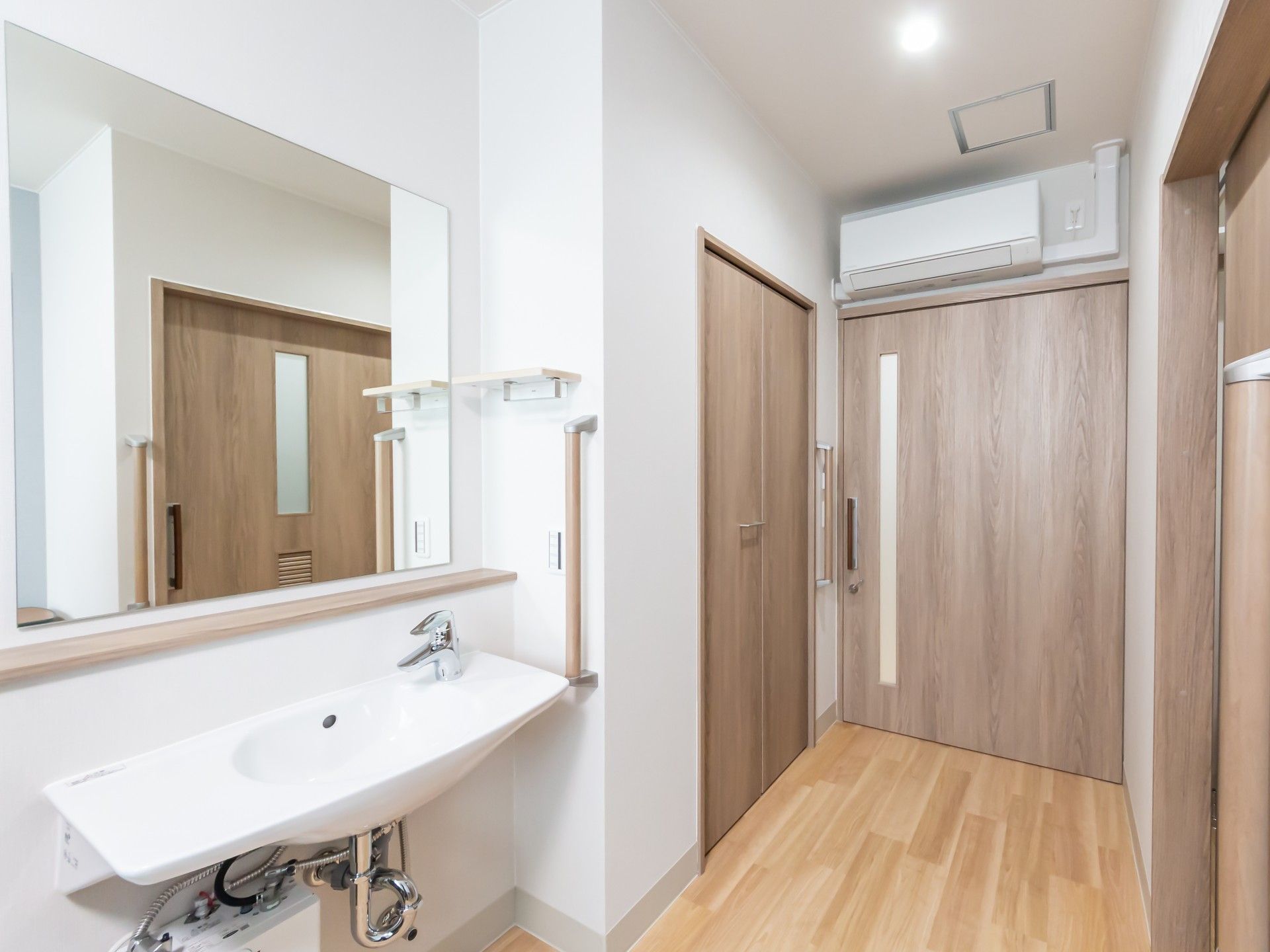 手洗い場と木製ドアの廊下