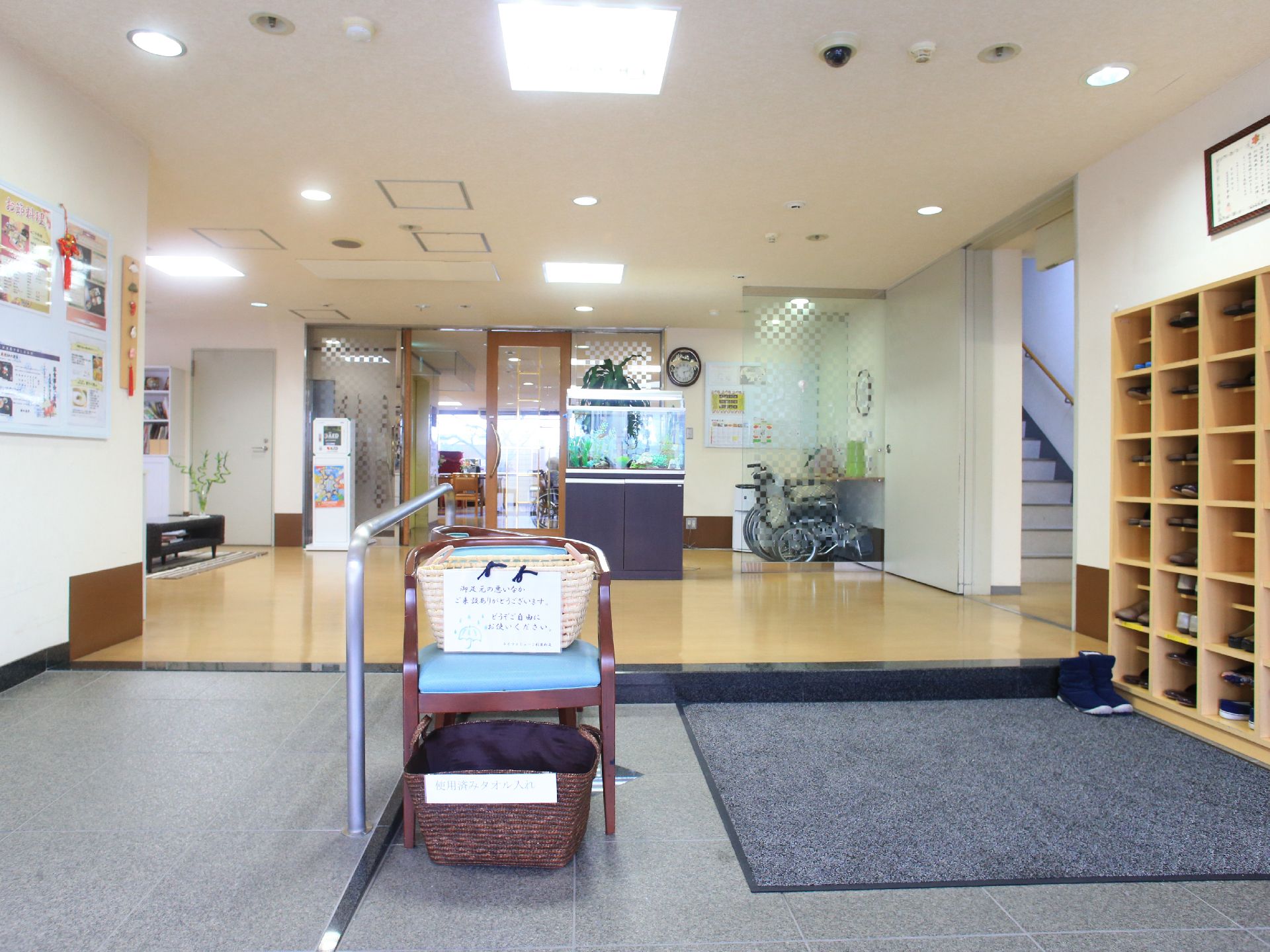 玄関の左手にはスロープが用意されており手すりもついている。右側にはマットが敷かれ壁際に下駄箱が設置されている。