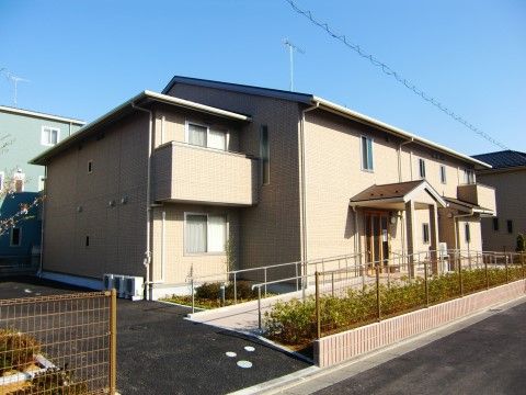 大きな一軒家のような外観の２階建ての建物。施設の左右から玄関前へ向かって、手すりのついたスロープが設置されている。