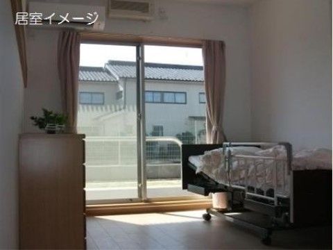 居室には１壁面に大きなガラス戸が設置され、ベランダが付いている。近隣の建物との間にはゆったりとした空間があり、自然光が注いでいる。