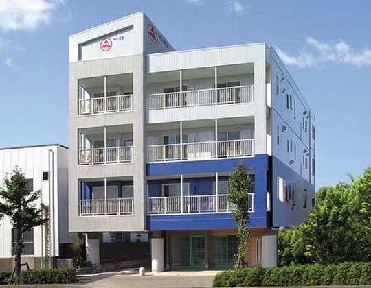 施設は茶色を基調とした外壁で、４階建ての建物となっている。１階部分には右に玄関があり、左にコンビニがある。