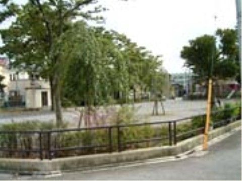 公園のまわりには腰高ほどの黒い柵が設置されている。そこにはさまざまな植物や木が植えられている。奥には住宅が見える。
