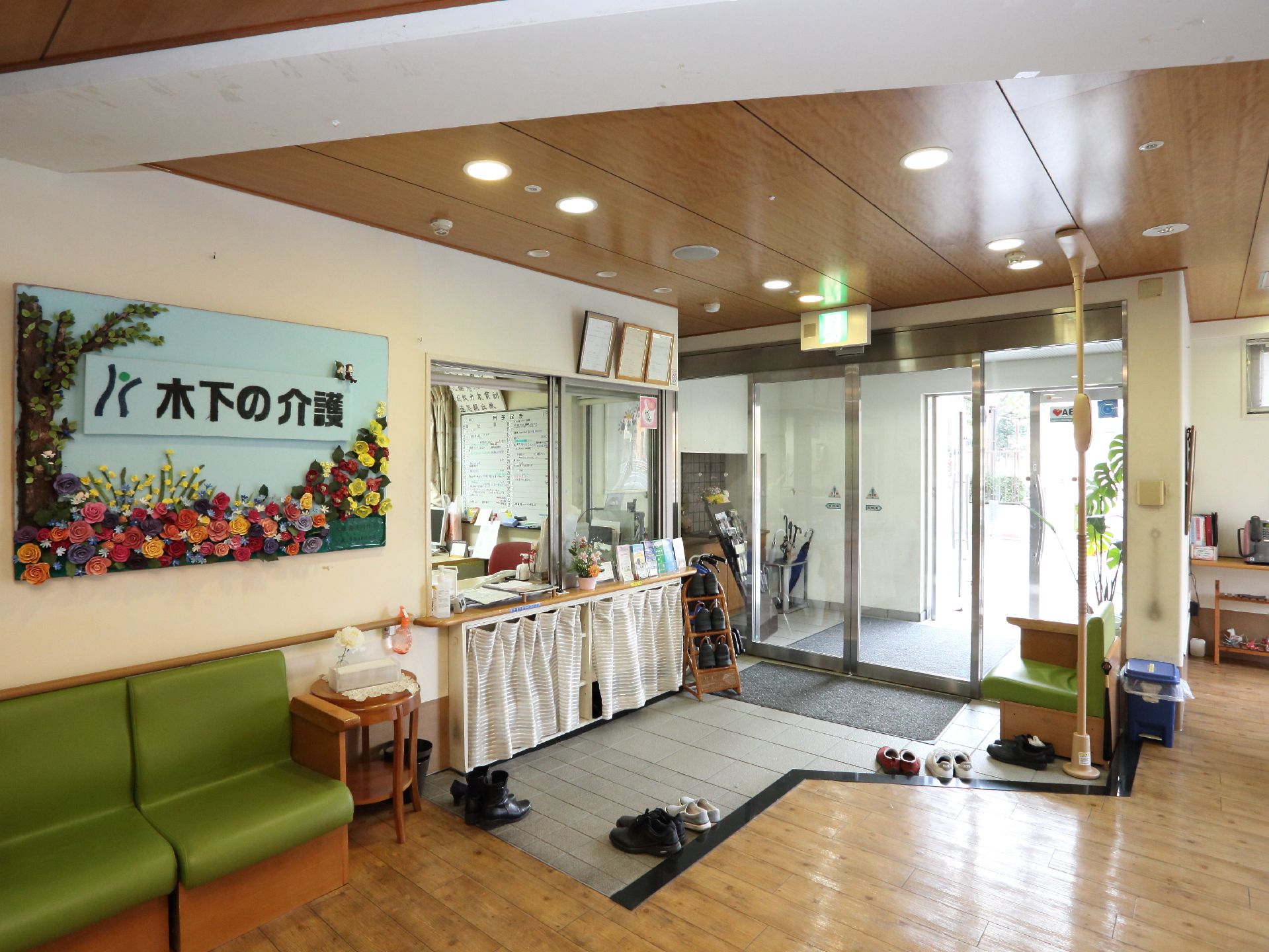 屋外へはバリアフリーで繋がっており、入り口の受付カウンターの下の棚は目隠しがされている。左側にはグリーンの椅子が置いてある。