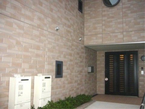 薄いブラウン系のタイル調の外観である。フラットな玄関のドアは、ダークブラウンを基調としたどっしりとした印象である。