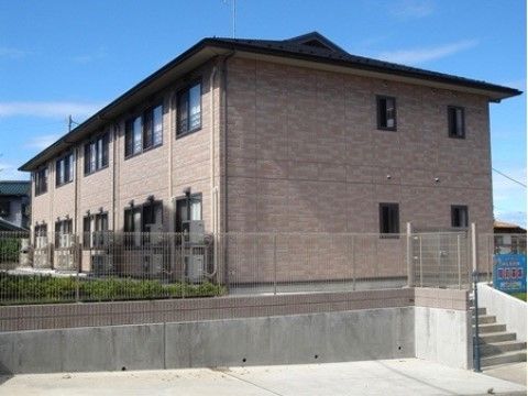 茶系の２階建ての箱型の外観は、アットホームな雰囲気である。敷地内には、緑豊富な植栽を取り入れ癒しの空間を設けている。