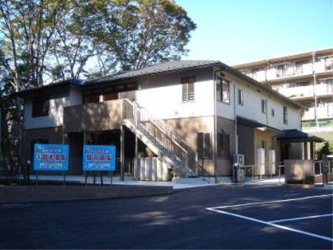 ２階建てのツートンカラーの施設の外観。側に大きな木があり、夏期は葉が生い茂り影を作ってくれるので、涼しくて快適である。