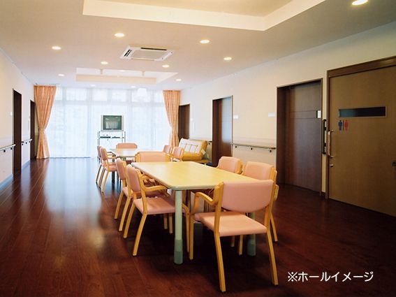 壁一面の大きな窓から光が差し込む、テーブルとイスが並ぶリビング