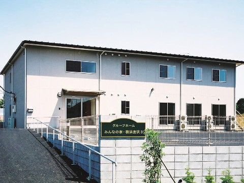 手前にスロープが設置されている、白い外壁に窓が並ぶ2階建ての建物