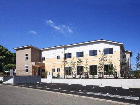 明るい色調の2階建ての建物で、日当たりもとてもよい環境にある。エントランス脇には駐車スペースも十分に確保している。