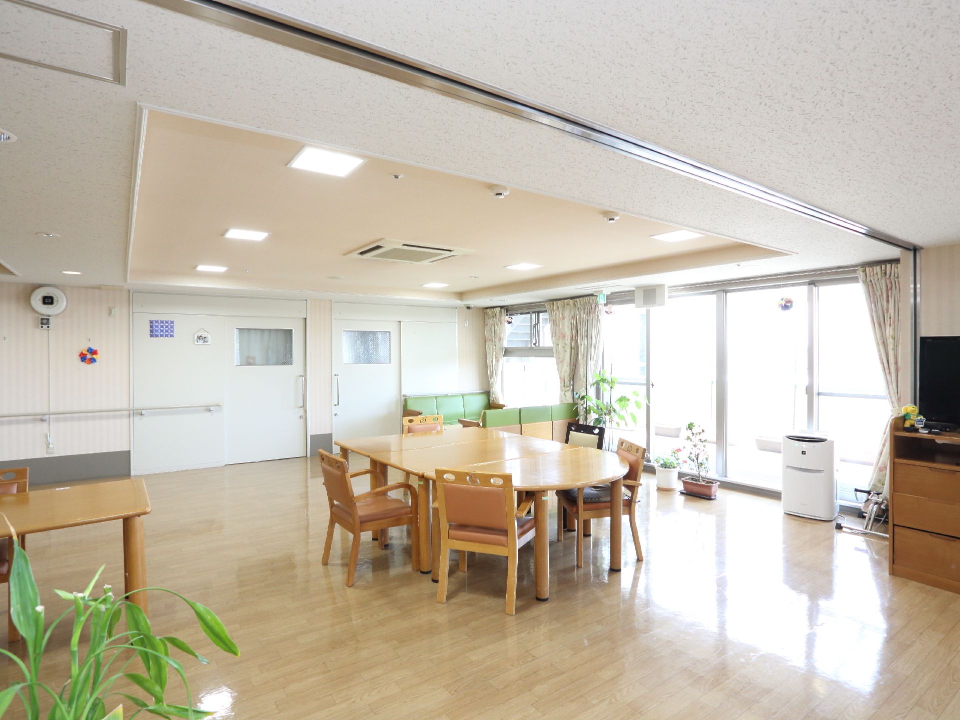 大きな窓から日が差し込む、テーブルセットが設置された明るいリビング