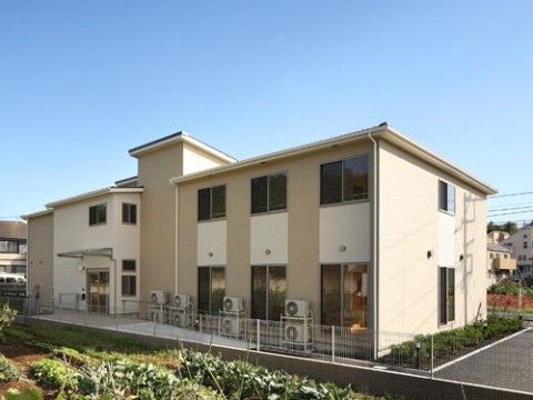 周辺に緑や畑、住宅が立ち並び、大きめの窓がついた2階建ての建物
