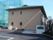 施設の建物は２階建てで、緑の屋根にベージュ系の外壁が設けられている。建物の前には駐車場が設置されている。