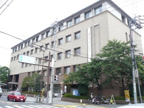 地域にある区役所の建物は５階建てで、外壁の色はベージュ系である。建物の周囲には木々が植えられている。