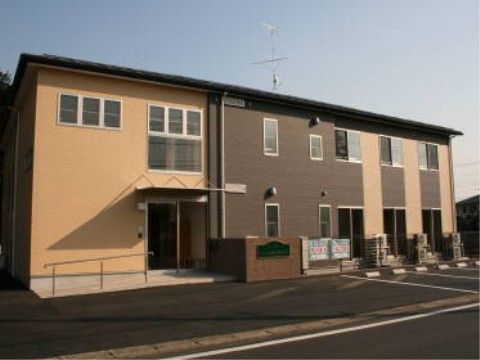ツートーンカラーの外壁をした、入り口に向かって緩やかなスロープのある建物