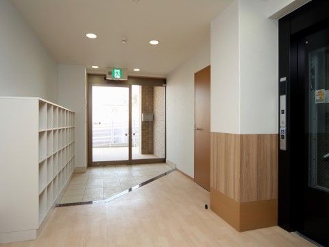 バリアフリー構造の明るい玄関ホールである。自動ドアの上には、非常灯を取り付けている。入居者様が安全な生活を送れる工夫をしている。