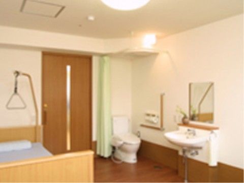 洗面台とトイレが備え付けられた個室タイプの居室である。ベッドの横には、介護用リフトが用意されている。