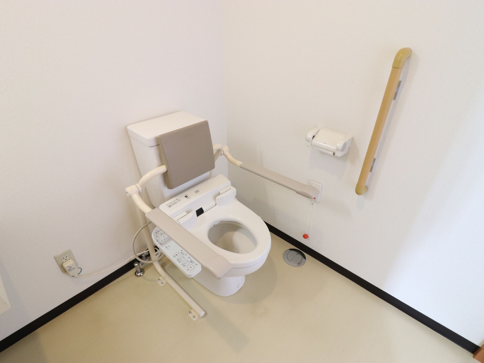 トイレは温水洗浄便座付きである。タンクの前面には背もたれ用のパッドがあり、左右には可動式の手すりが設置されている。