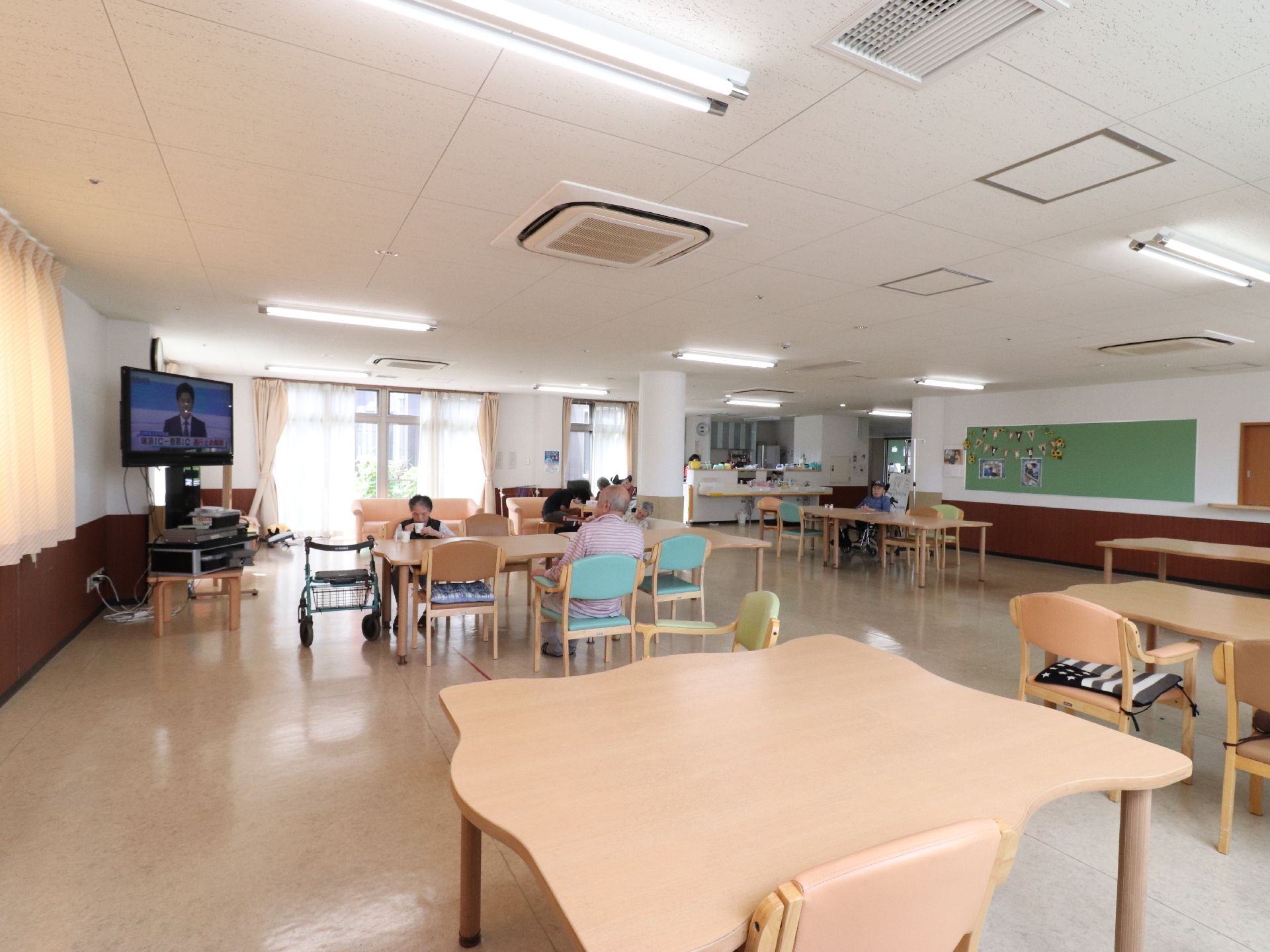 テレビとテーブル、椅子が置かれた広いリビングで自由に過ごす入居者