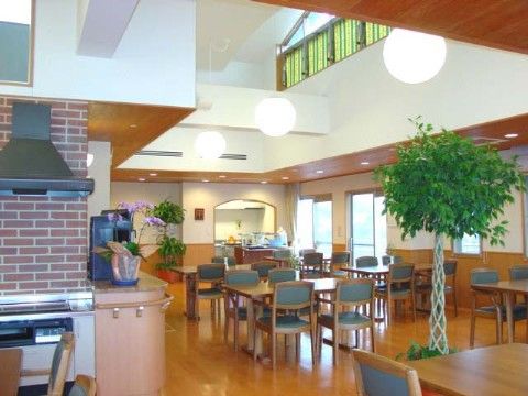 明るい陽光が入り、吹き抜けが開放的な食堂である。花や観葉植物も飾られているリラックスした空間で、お食事を楽しんでいただける。