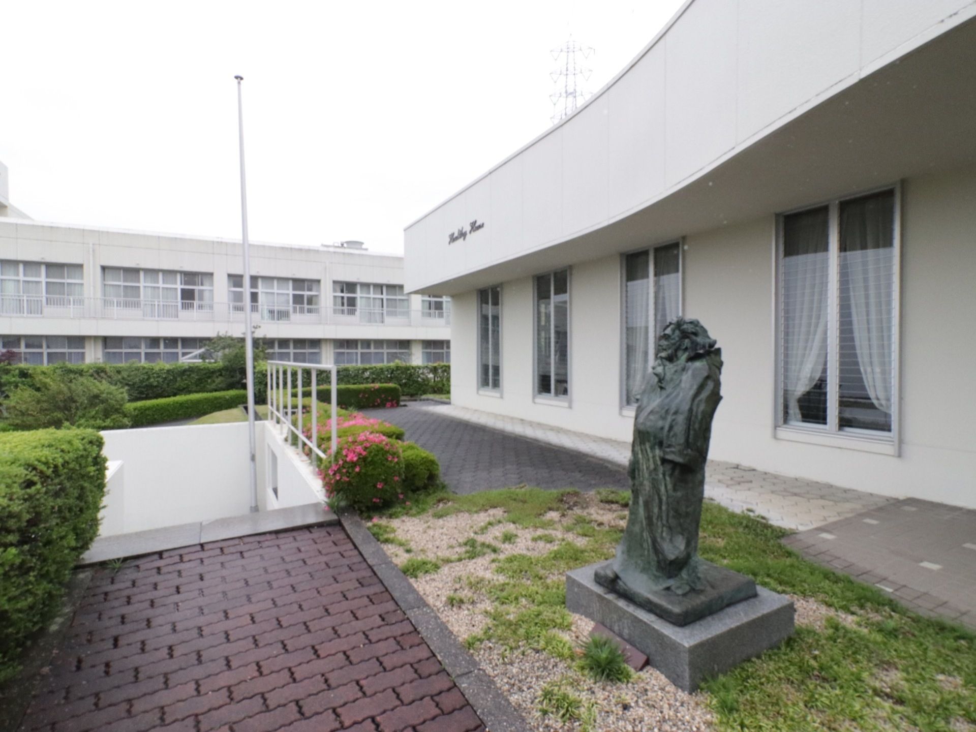 写真奥と、手前に、白い建物が建っているのが見える。奥の建物の窓には、白い柵の付いたベランダが設置されている。