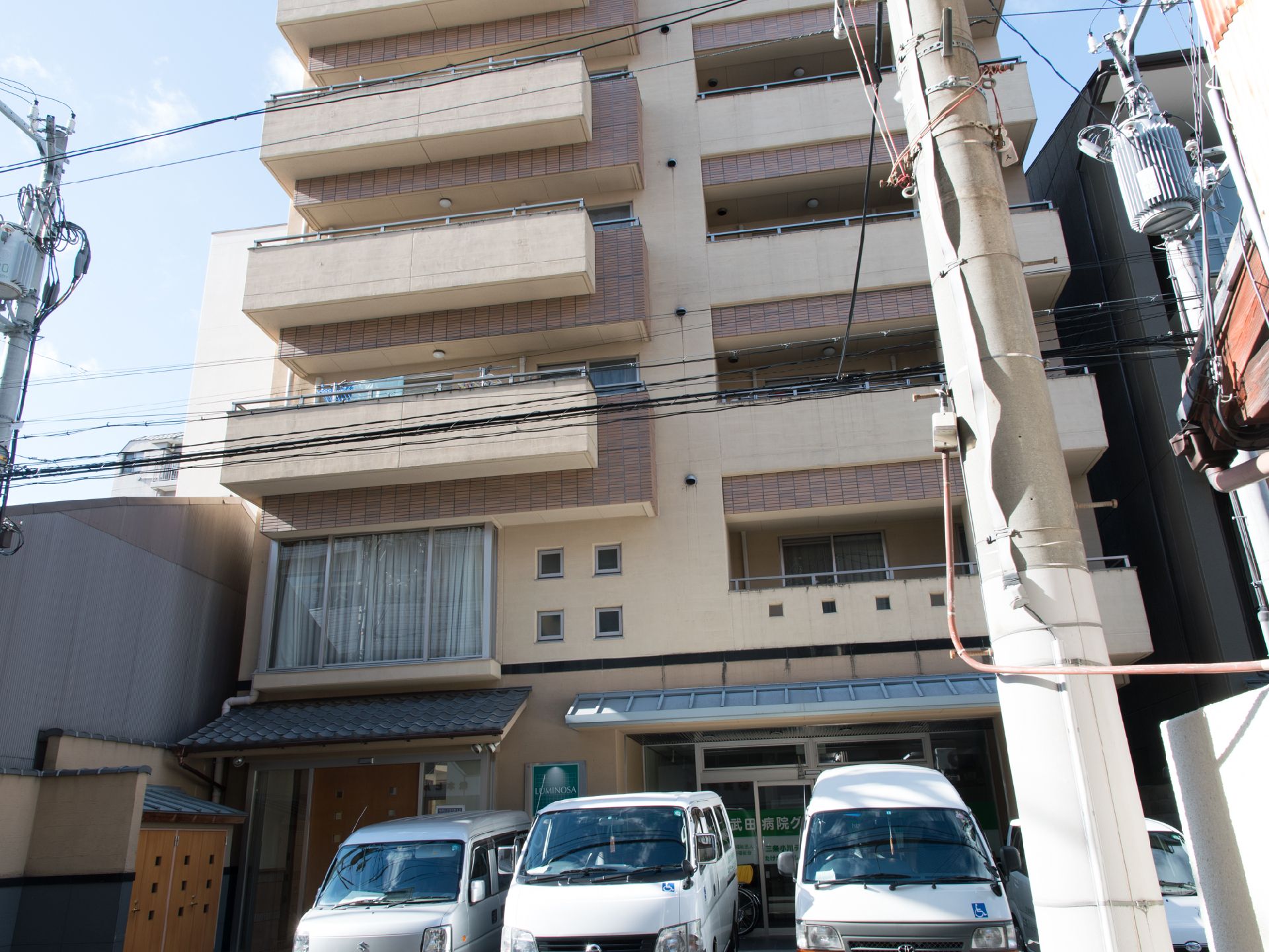 「ルミノーサ三条小川」の外観。茶系の落ち着いた色合いの建物。
