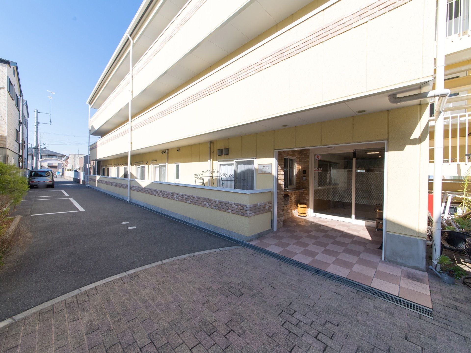 閑静な住宅地に立地している施設の外観。ベージュの外壁にレンガをあしらい、おしゃれな雰囲気になっている。敷地内に駐車スペースがある。