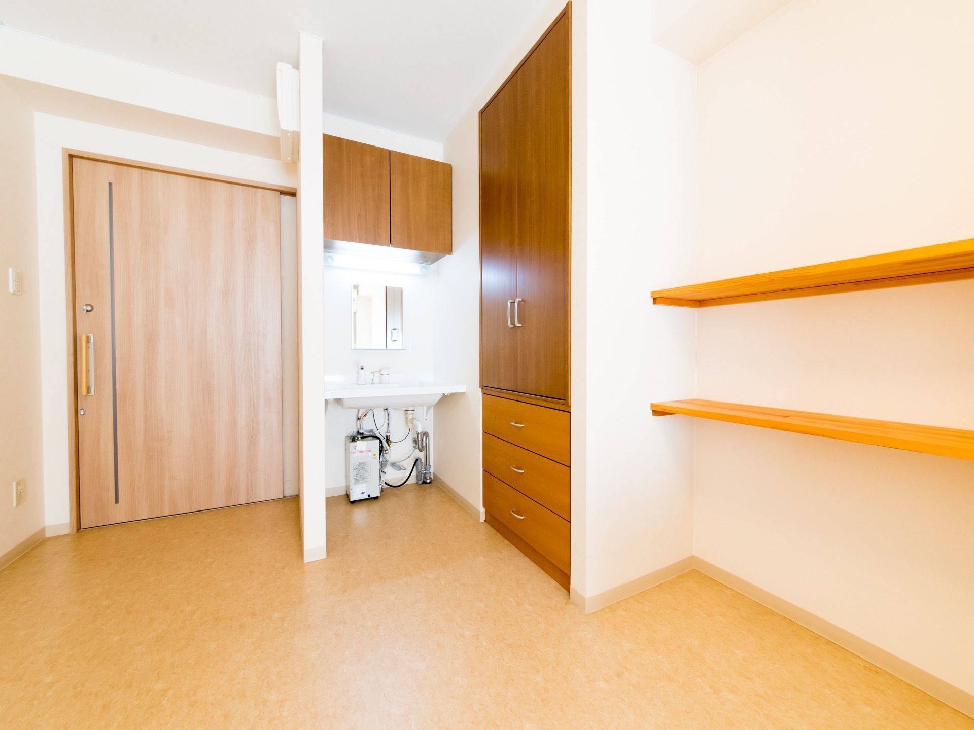 幅の広い引き戸が設置されている広々とした居室。入り口周辺には洗面台の他、引き出し付きの収納スぺ―スが設けられている。